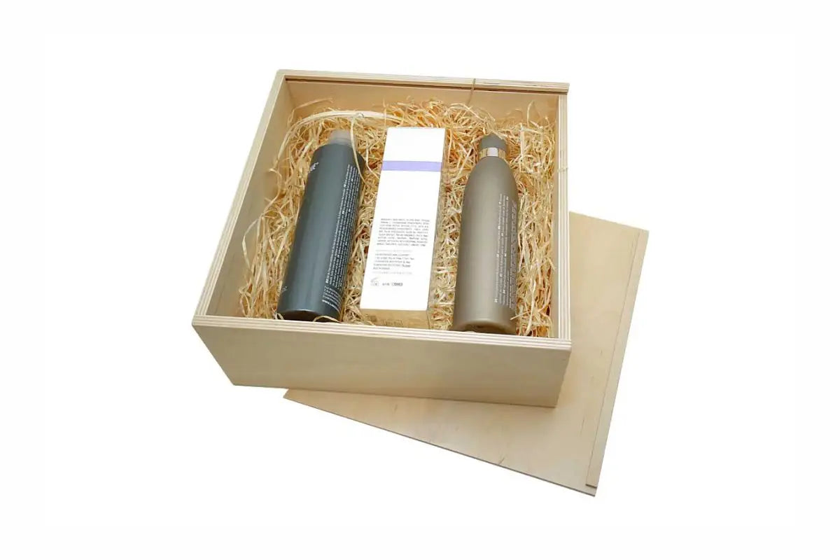 Genussbox aus hellem holz mit schiebedeckel und strohfüllung enthält zwei matte flaschen und einen weißen produktbeileger